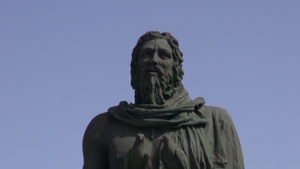 Sculpture of guanche with two birds on a stick and a man walking by on ocean shore in Candelaria — Stock Video