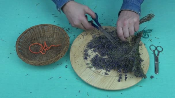 Hombre cortando lavanda seca en una placa de madera con tijeras — Vídeo de stock