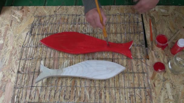 Живопись деревянных рыб красной краской — стоковое видео