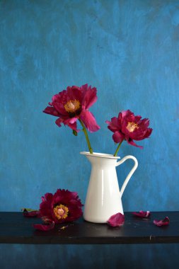 Beyaz sürahi içinde güzel kırmızı şakayık çiçekleri