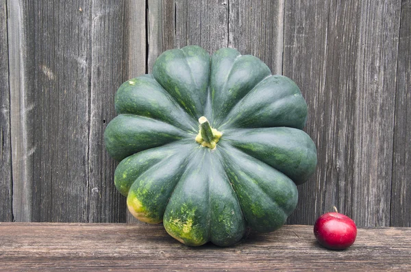 Großer grüner Kürbis und kleiner roter Apfel — Stockfoto