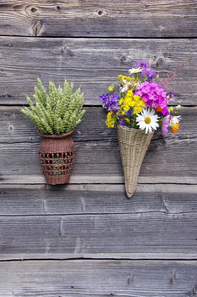 Две плетеные корзины с цветами и пшеничными ушами на стене — стоковое фото