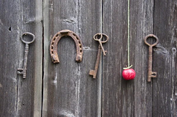 Chiave antica, ferro di cavallo e mela rossa su vecchia parete di legno — Foto Stock