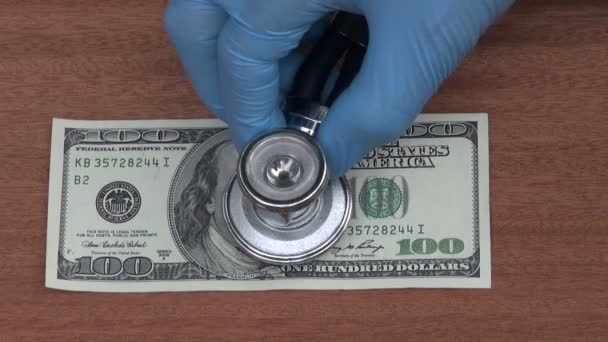 Économiste avec stéthoscope regardant l'état des billets en dollars — Video