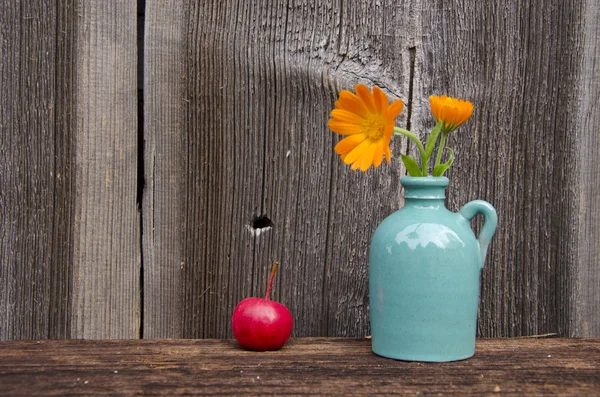 Marigold flowers in small vase and red apple — Stock Photo, Image