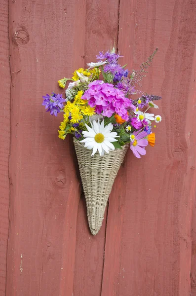 Hermosas flores de verano en canasta de mimbre en la pared — Foto de Stock