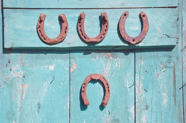 Four rusty horseshoe on farm door — Stock Photo, Image