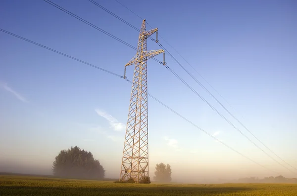 Torre de alto voltaje post.High en el campo de la granja en la niebla —  Fotos de Stock