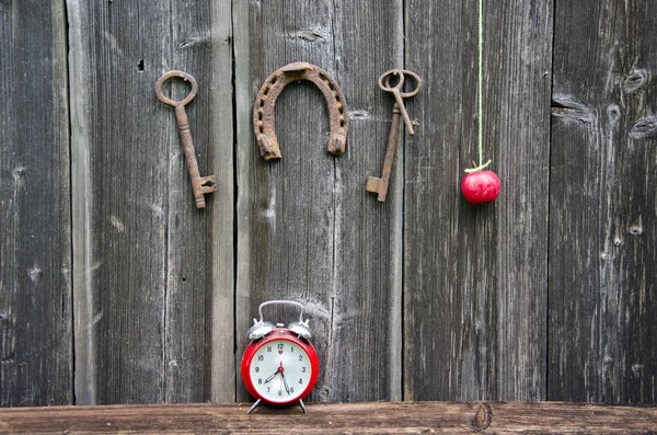 Ferro di cavallo, mela, chiave e orologio su parete di legno — Foto Stock