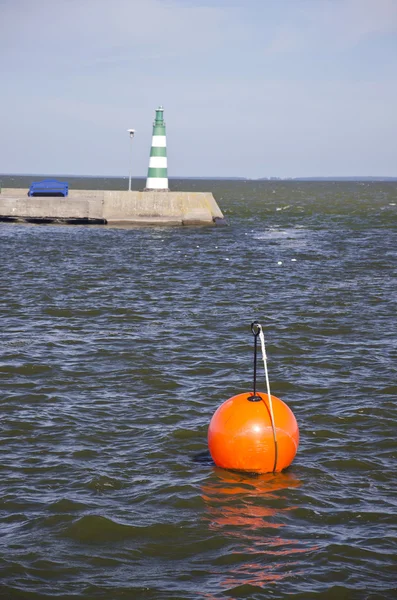 Orange buoy and lighthouse in sea dock — Stock Photo, Image