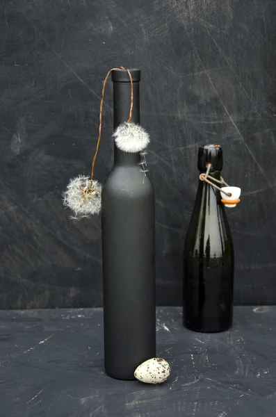 Siyah şişe ve karahindiba tohum ile natürmort — Stok fotoğraf