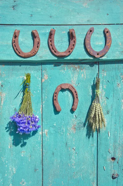 Fer à cheval, bouquet de blé et bleuet sur la vieille porte de la ferme wodoen — Photo