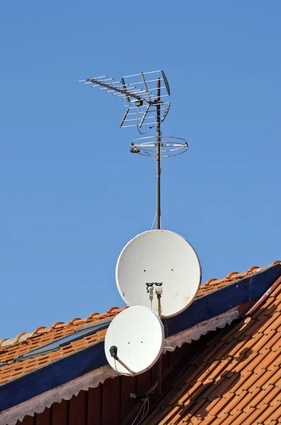 Satellite dishes on a tiled roof Stock Picture