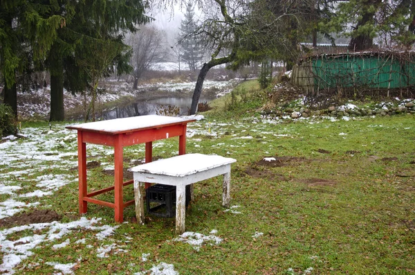 Zwei Holztische mit dem ersten Schnee im Herbst im Bauerngarten — Stockfoto