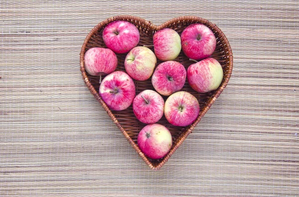 Manzana fresca en canasta de mimbre corazón de madera — Foto de Stock