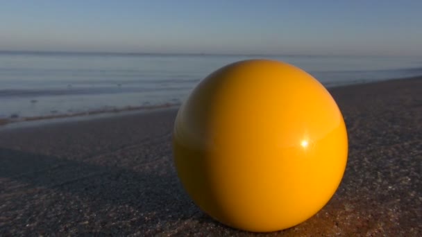 Bola de billar amarillo en la playa del mar de verano en la luz del amanecer de la mañana — Vídeos de Stock