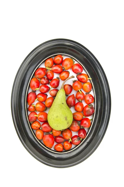 Red medical rose hips fruit and one pear in oval frame — Stok Foto