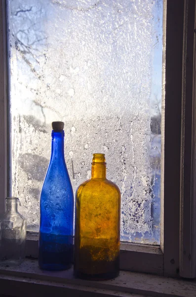 Deux vieilles bouteilles sur la ferme gelée fenêtre d'hiver — Photo