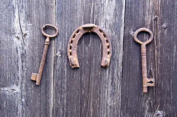 Dos viejos oxidados clave histórica y símbolo de la suerte herradura en la pared — Foto de Stock