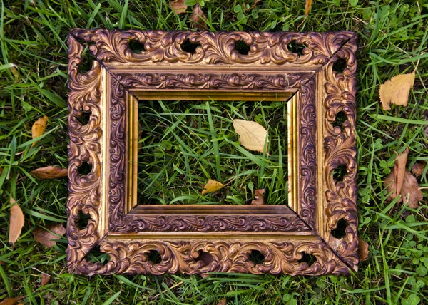 Antigue  picture frame on autumn grass with yellow leaves — Stock Photo, Image