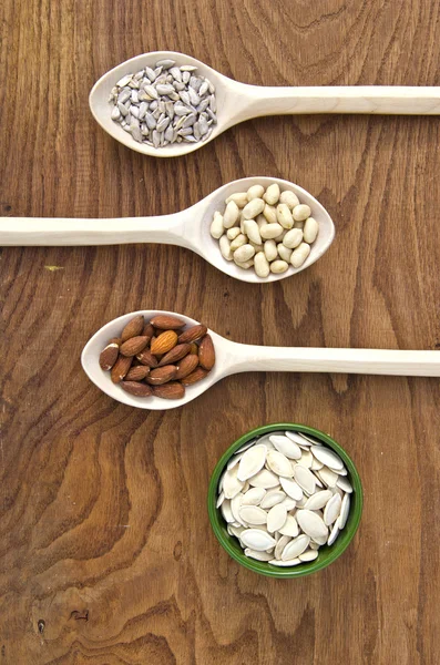 Wooden spoons with different kinds of seeds and nuts — Stock Photo, Image