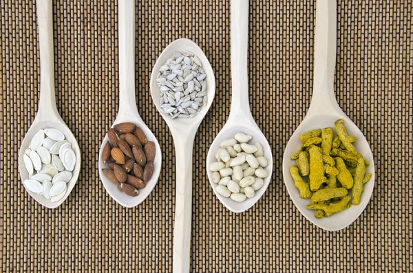 Wooden spoons with different kinds of seeds and nuts — Stock Photo, Image