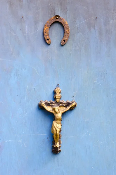 Страдания от распятия Иисуса Христа и ржавой подковы на старой голубой стене — стоковое фото