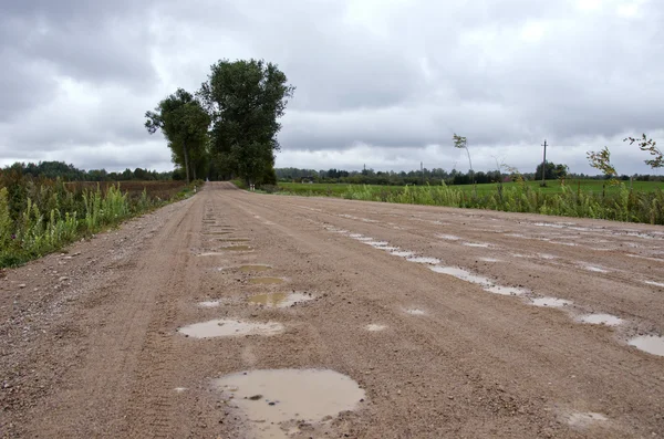 Rural onverharde weg met plassen na regen — Stockfoto