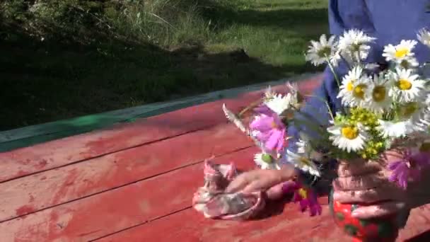 Limpeza de mesa de madeira no quintal e colocar vaso com flores — Vídeo de Stock