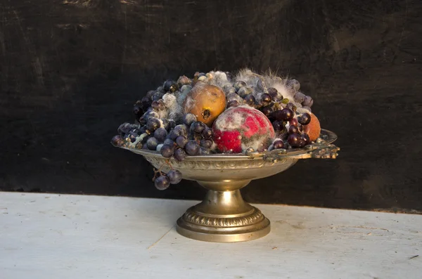 Antika ayaklı tabak vazo ile çeşitli çürük meyve — Stok fotoğraf