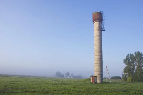 Paisagem rural da manhã com torre de água e nevoeiro névoa — Fotografia de Stock