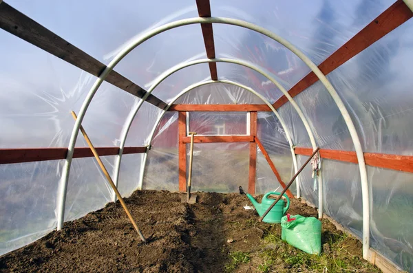 Early spring time greenhouse inside construction with gardener tools — Stock Photo, Image