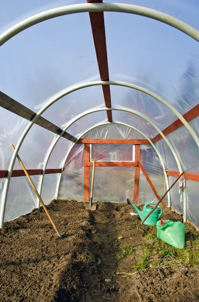 Invernadero de primavera temprana dentro de la construcción con herramientas de jardinero y suelo —  Fotos de Stock