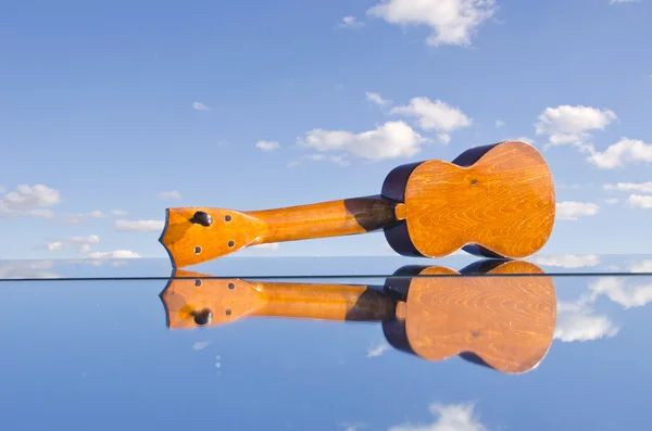 Kleine kinderen gitaar speelgoed op spiegel en hemel — Stockfoto