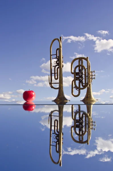 Retro brass musical instruments on mirror and apple — Stock Photo, Image