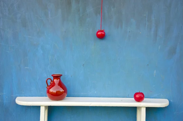 Red apple and red vase on white shelf — Stock Photo, Image