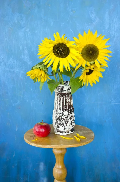 Antike Vase mit Sonnenblumen und rotem Apfel auf dem Tisch — Stockfoto