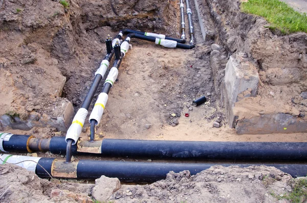 Plastic modern technology black heating pipes in trench near house — Stockfoto