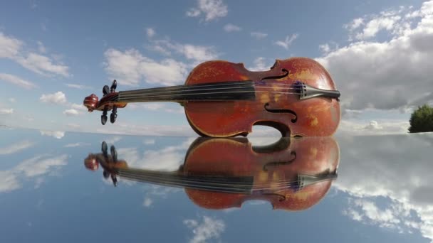 Viejo instrumento de música de violín usado en movimiento espejo y nubes. Concepto de arte, timelapse 4K — Vídeo de stock