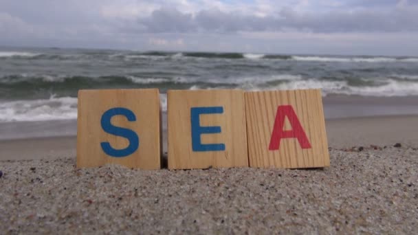 Слово море, сделанное из буквенных кубиков у моря — стоковое видео