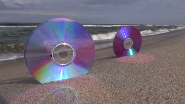 Två CD-skivor på sea beach sand och vågor — Stockvideo