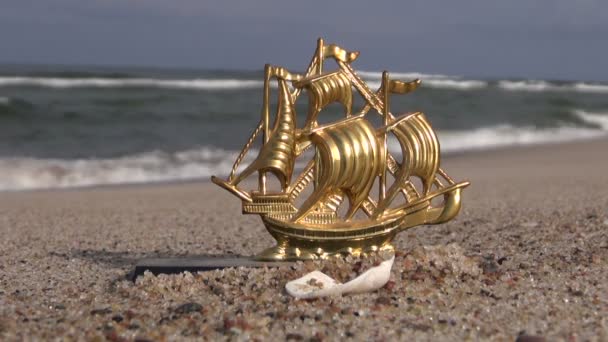 Seascape with decorative toy  golden ship in sand — Stock Video