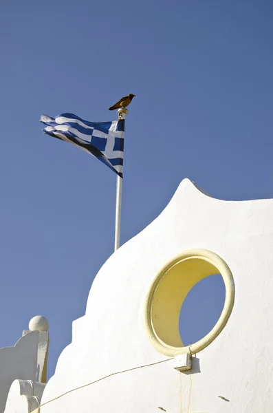 Grekisk flagga vajande på antik byggnad med kråkan sitter på toppen — Stockfoto