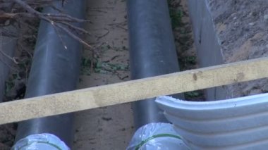Evin bir hendekte iki siyah su ısıtma boruları