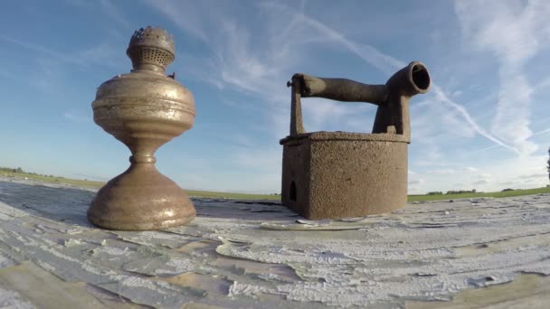 Ferro enferrujado histórico e lâmpada de querosina na mesa velha e nuvens movimento, timelapse 4K — Vídeo de Stock