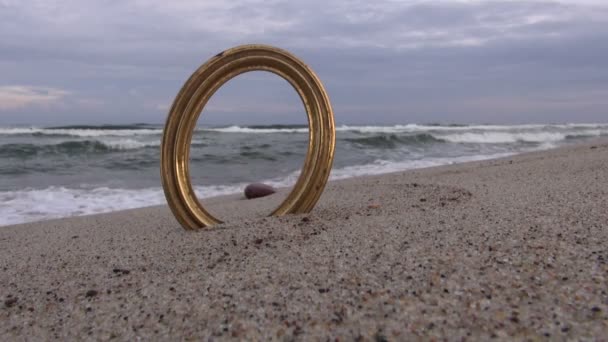 Морський пейзаж із золотою порожньою рамкою, застрягнутою у піску — стокове відео