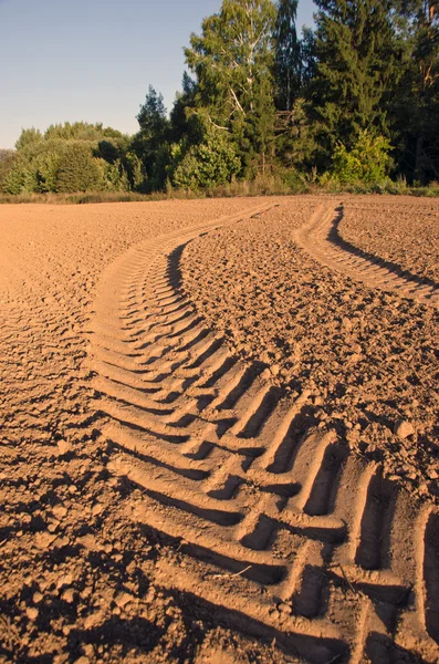 Trekker tracks in vers geploegd bodem veld zonnige dag — Stockfoto