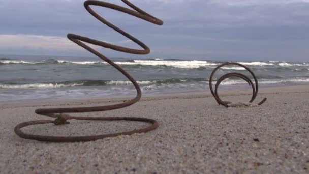 Duas molas metálicas enferrujadas na praia do oceano areia e ondas — Vídeo de Stock