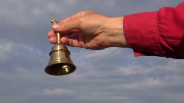 Рука держит красивый металлический медный колокол и звонит в него — стоковое видео
