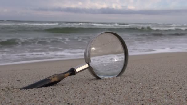 Antikes Vergrößerungsglas auf Sand am Meer — Stockvideo